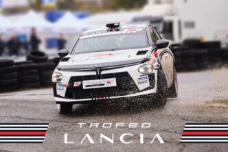 Lancia Ypsilon Rally4 HF driftend door een bocht tijdens de Trofeo Lancia. De rallyauto spat modder op terwijl hij de controle behoudt op het natte asfalt.