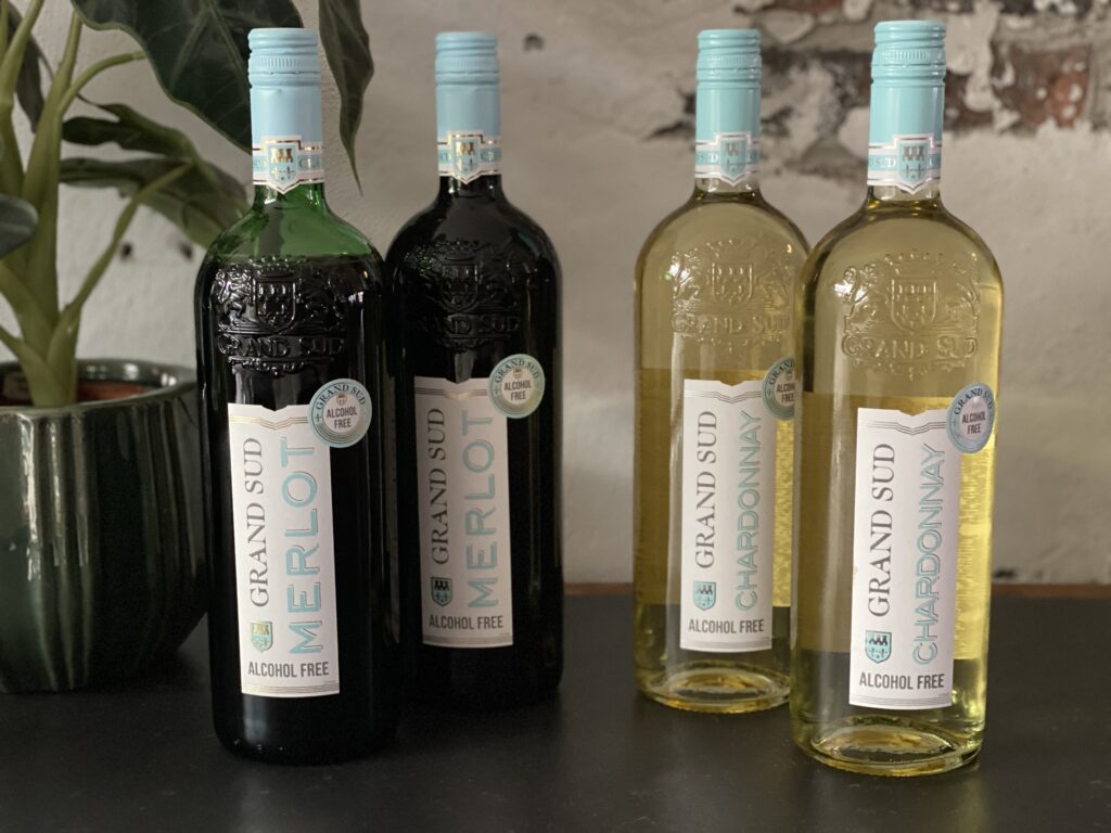 Vier flessen Grand Sud alcoholvrije wijn, Chardonnay en Merlot, op een tafel