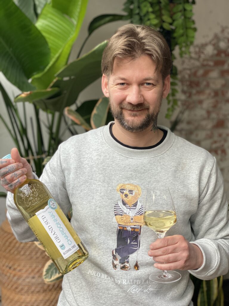 Jan Willem van B4men met een fles Grand Sud alcoholvrije Chardonnay en een ingeschonken glas