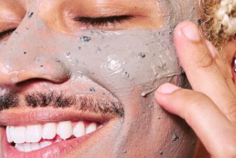 huidverzorging voor mannen. Man smeert creme in zijn gzicht en lacht