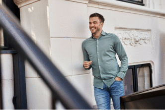 Man met mooie outfit leunt tegen muur